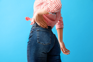 Woman wearing jeans on blue background, closeup