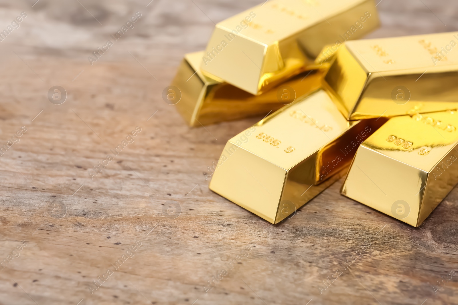 Photo of Shiny gold bars on wooden table. Space for text