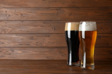 Photo of Glasses with different types of cold tasty beer on wooden table