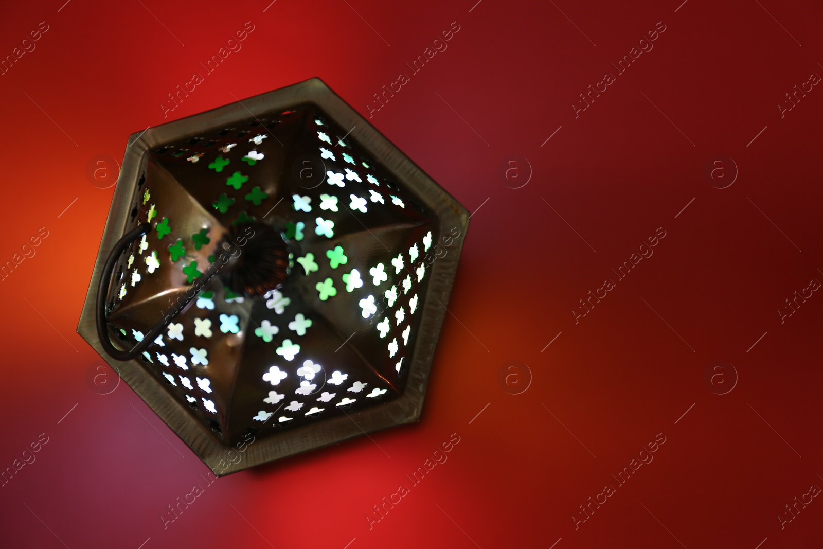 Photo of Decorative Arabic lantern on red background, top view. Space for text