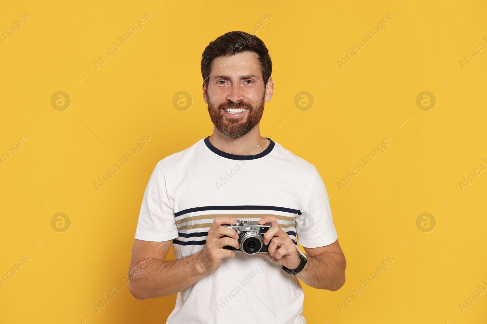 Photo of Man with camera on yellow background. Interesting hobby