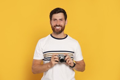 Photo of Man with camera on yellow background. Interesting hobby