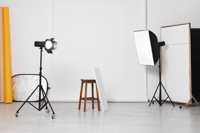 Photo of Different photo backgrounds, stool and professional lighting equipment in studio