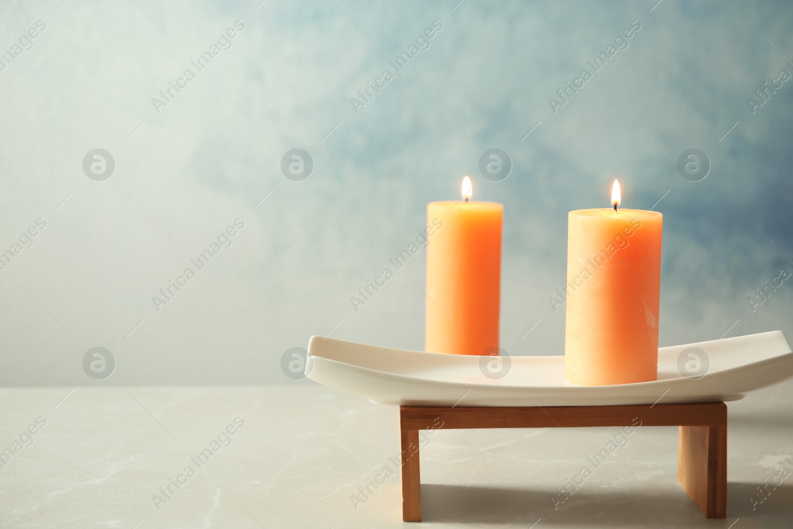 Photo of Decorative candles with stand on table against color background