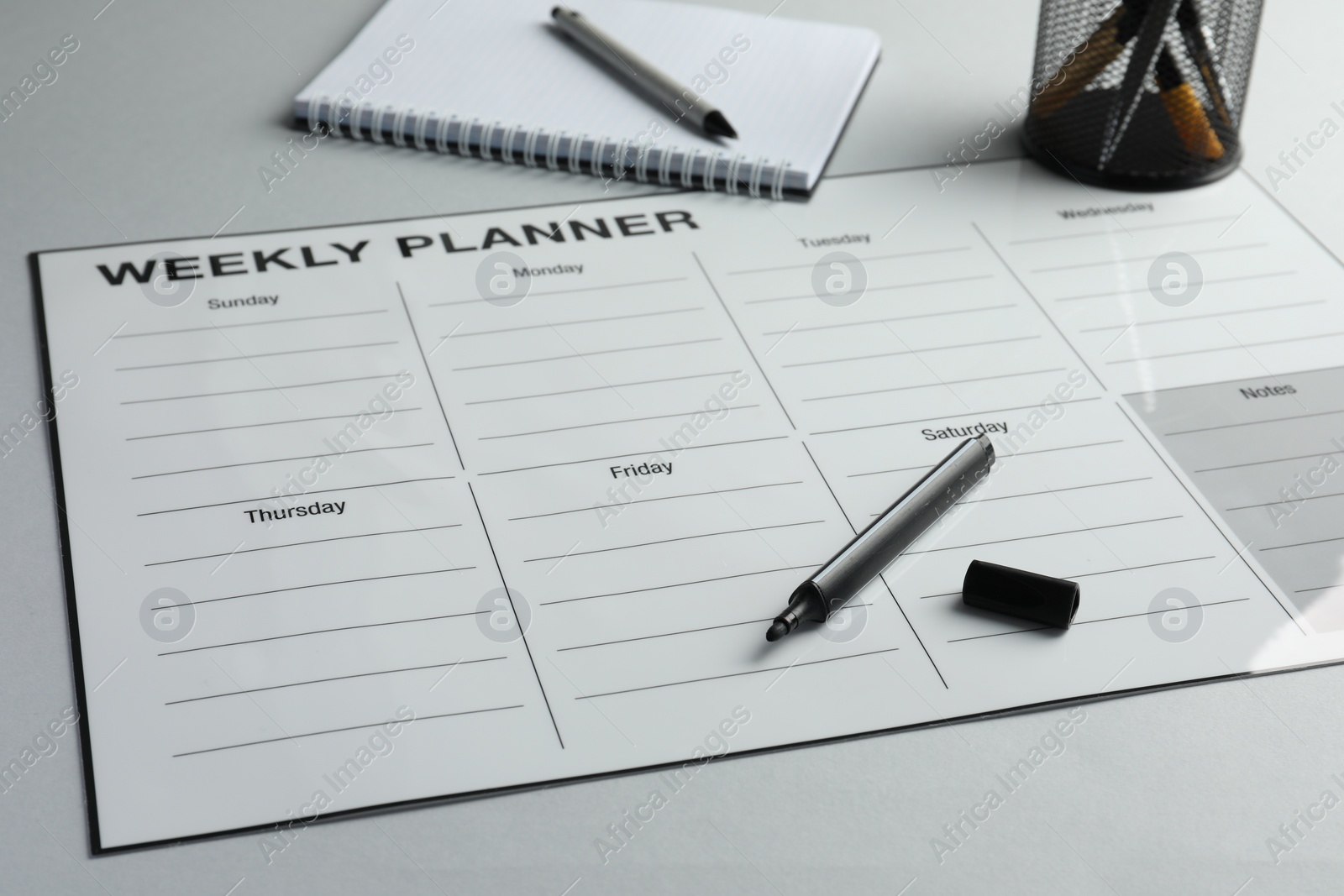 Photo of Timetable. Planner and black felt pen on grey table, closeup