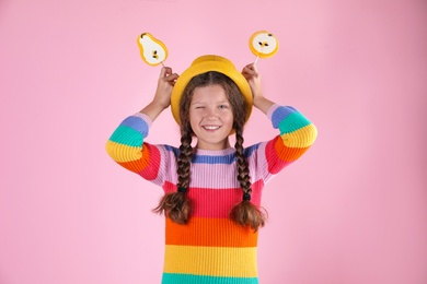 Little girl with candies on color background