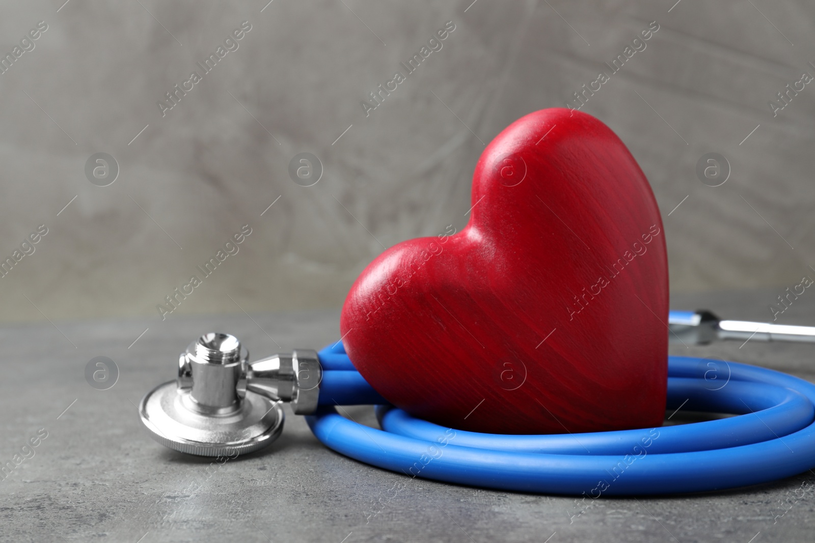 Photo of Red heart with stethoscope on grey background, closeup