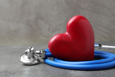 Red heart with stethoscope on grey background, closeup