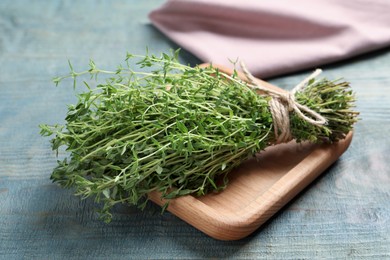 Photo of Bunch of aromatic thyme on light blue wooden table, closeup