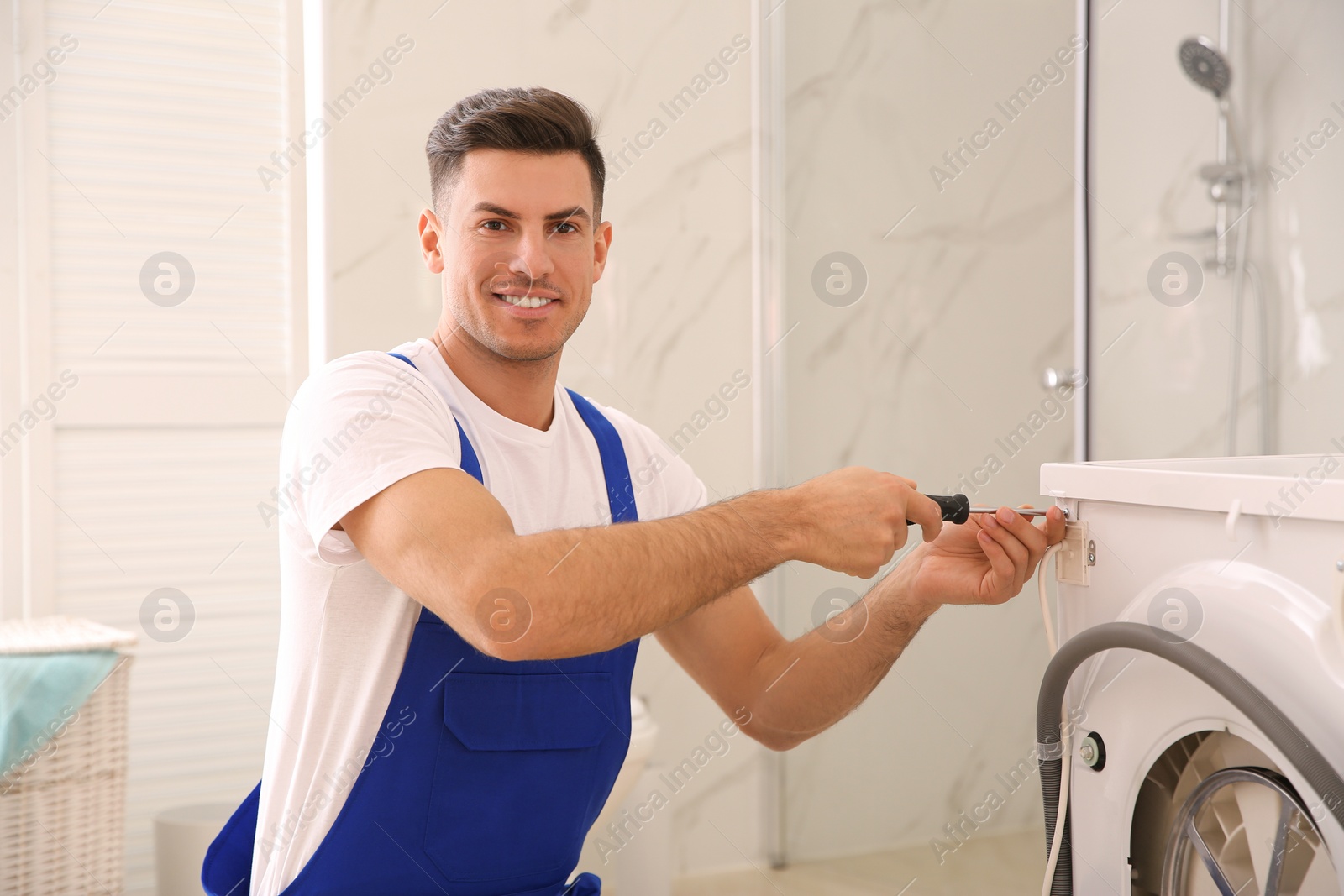 Photo of Professional plumber repairing washing machine in bathroom