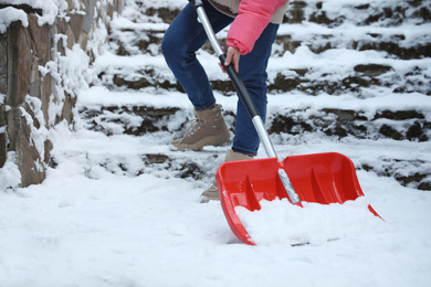 Woman cleaning snow with shovel outdoors on winter day, closeup