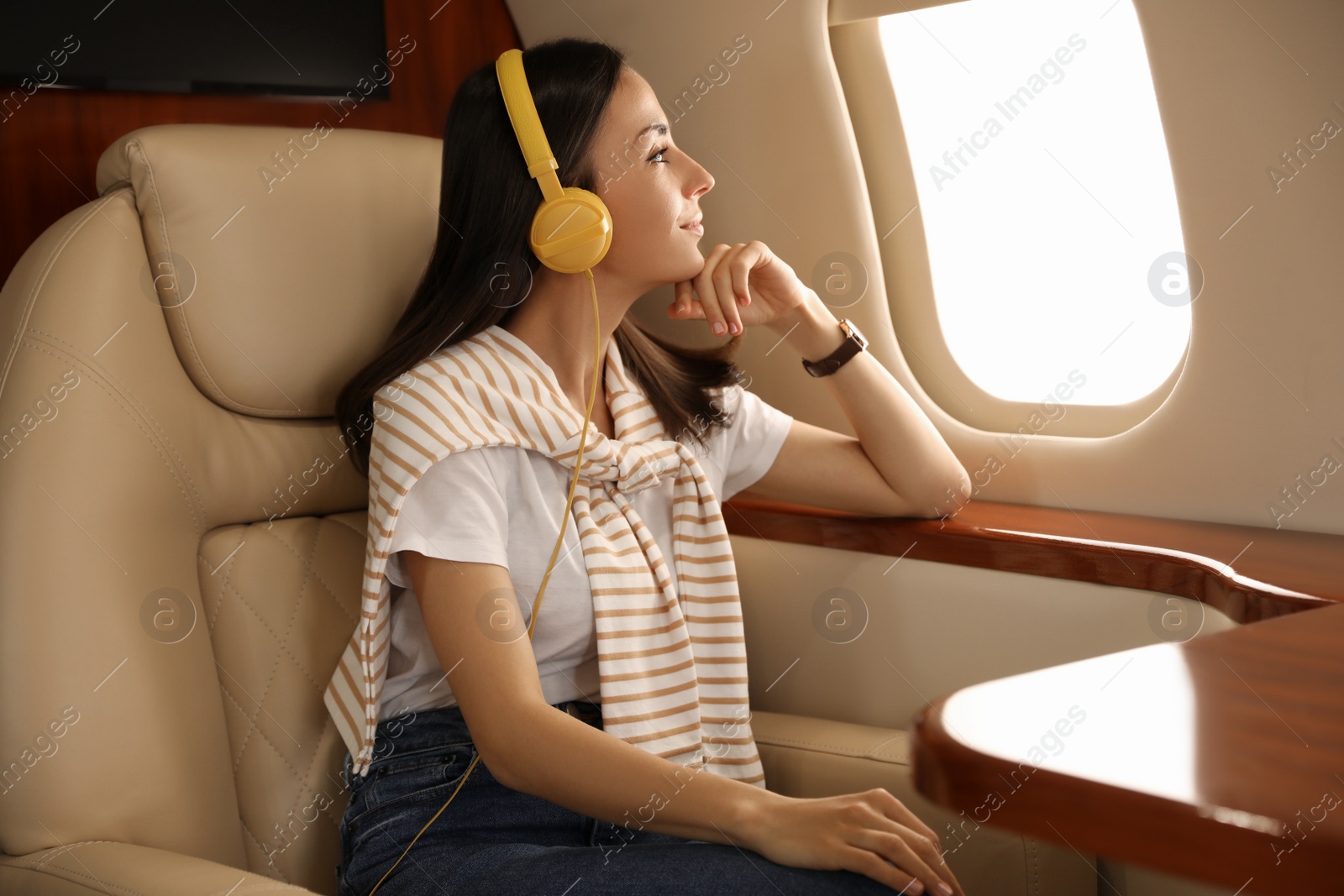 Photo of Young woman with headphones listening to music in airplane during flight