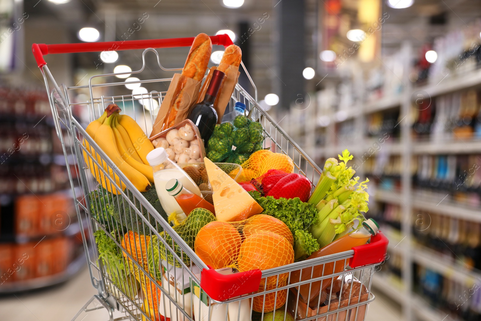 Image of Shopping cart with different groceries in supermarket