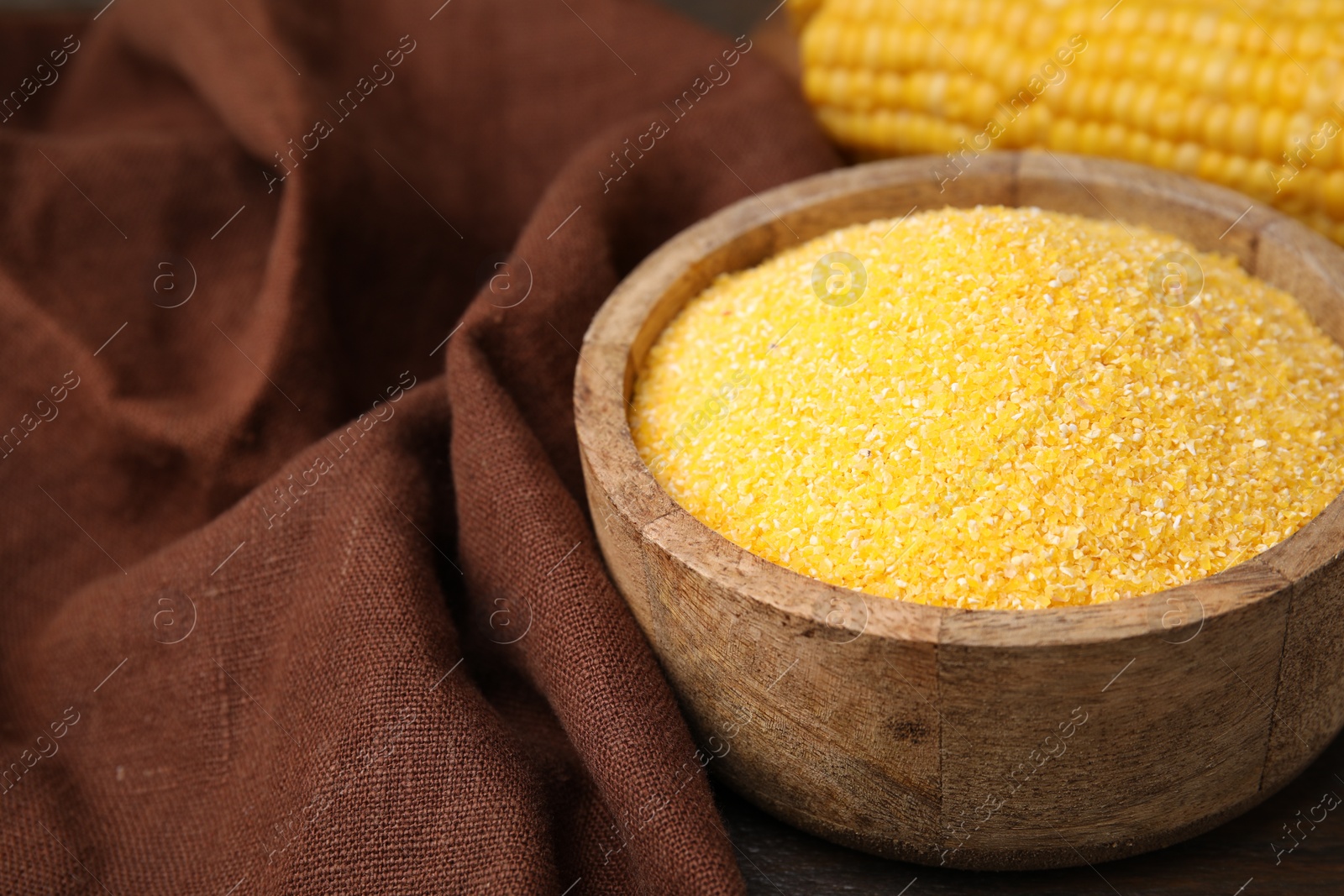 Photo of Raw cornmeal in bowl on table, closeup. Space for text