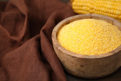 Raw cornmeal in bowl on table, closeup. Space for text