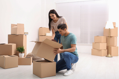Photo of Happy couple unpacking cardboard boxes in their new flat on moving day