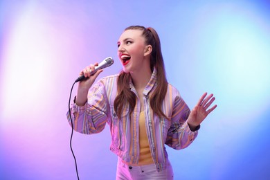 Emotional woman with microphone singing in color lights