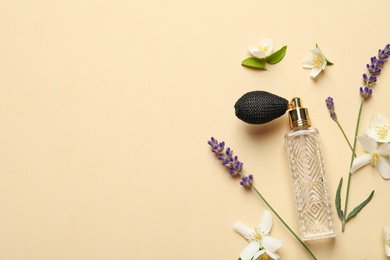 Flat lay composition with elegant perfume and beautiful flowers on beige background, space for text