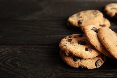Photo of Tasty chocolate chip cookies on wooden table. Space for text