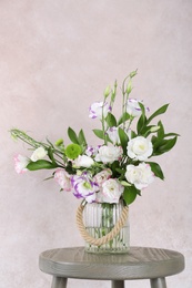 Vase with bouquet of beautiful flowers on table against color background. Space for text