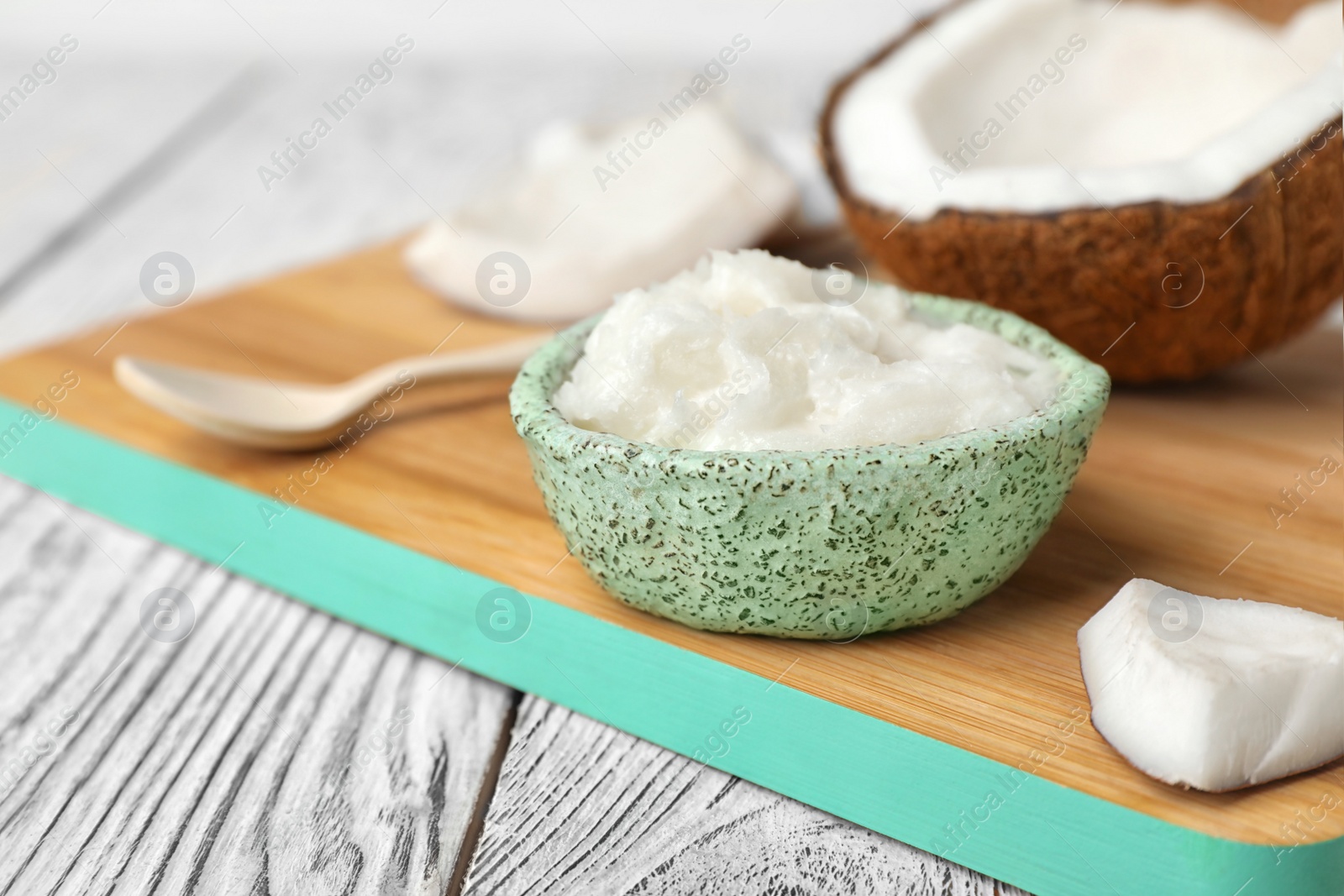 Photo of Bowl with fresh coconut oil on wooden board. Healthy cooking