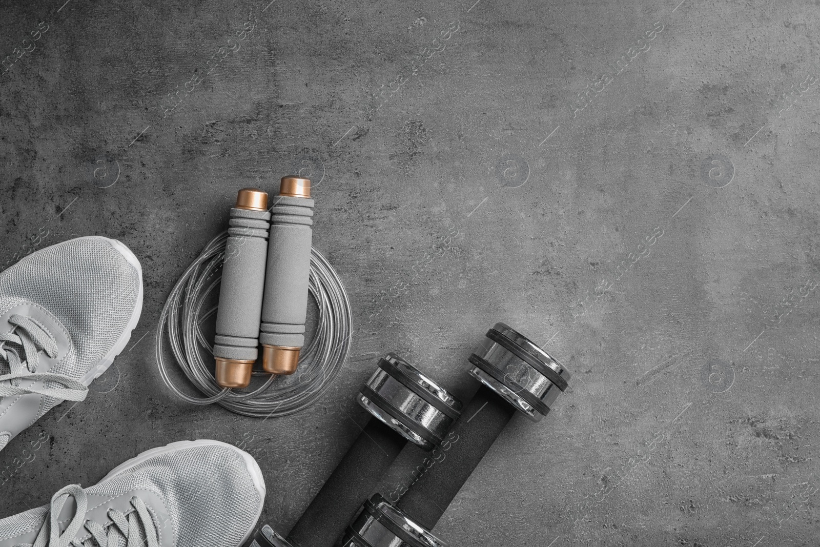 Photo of Flat lay composition with jump rope, gym equipment and space for text on grey background