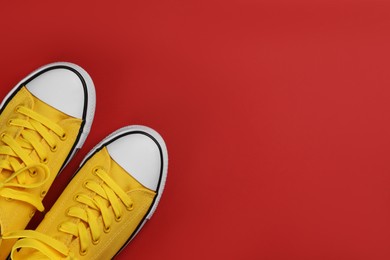 Photo of Stylish sneakers on red background, flat lay. Space for text
