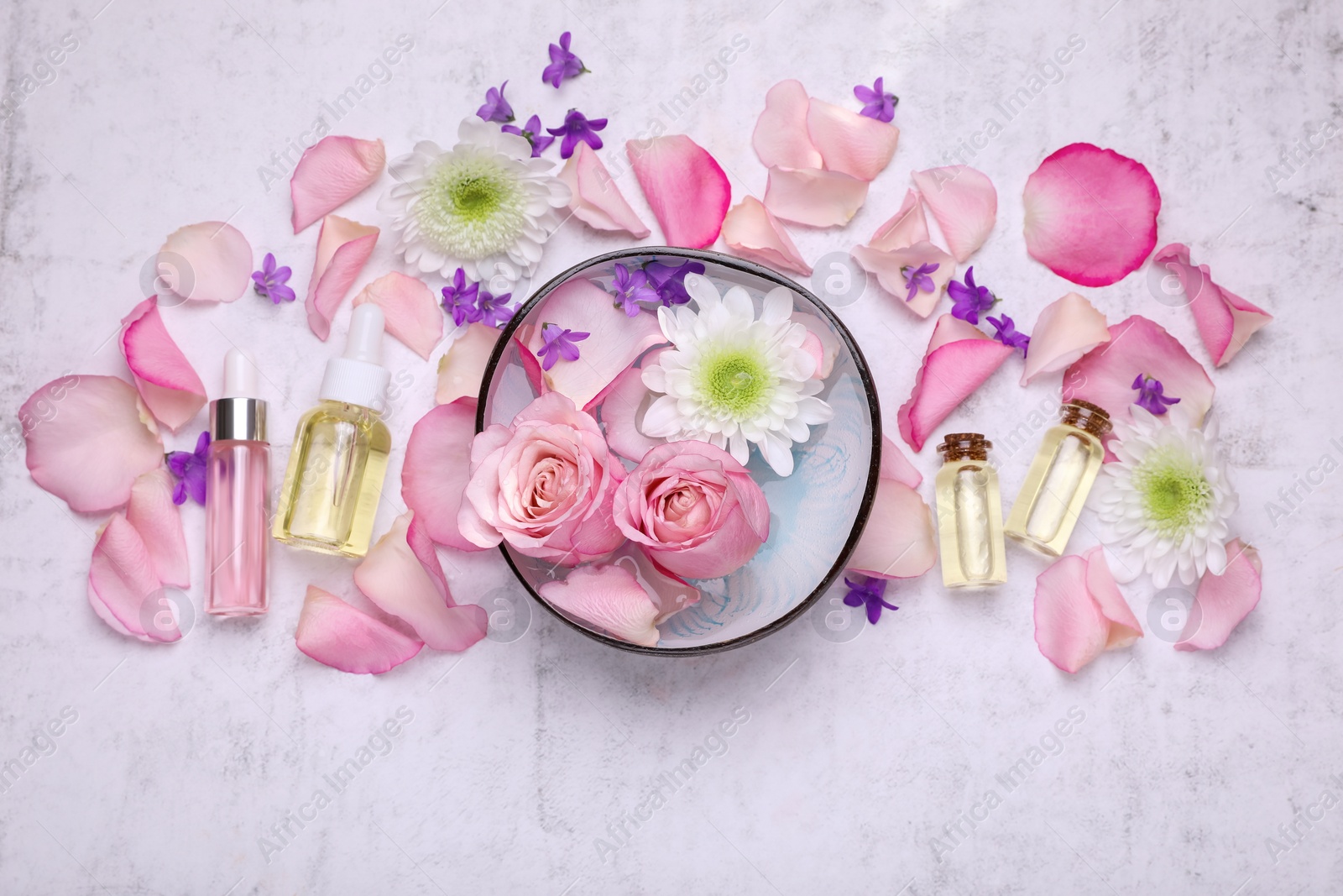 Photo of Flat lay composition with bowl of water and beautiful flowers on light table. Spa treatment