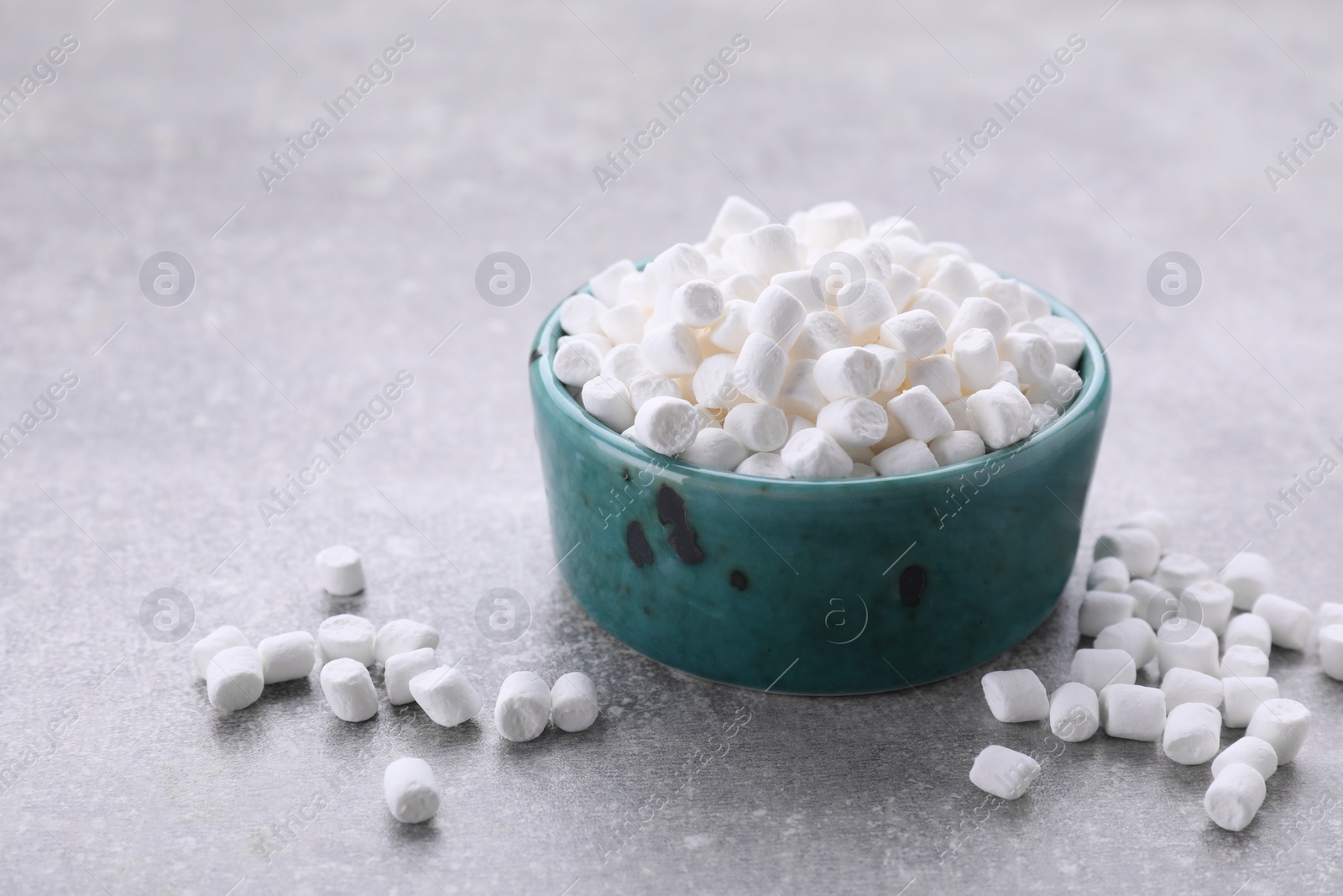 Photo of Bowl with delicious marshmallows on light gray background