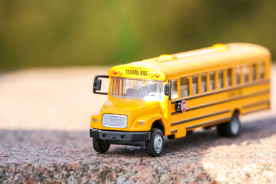 Photo of Yellow toy school bus outdoors on sunny day. Student's transport