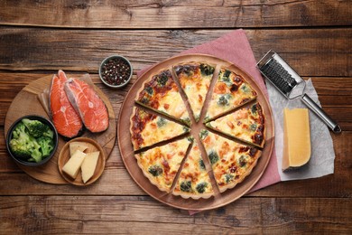 Delicious homemade quiche and ingredients on wooden table, flat lay