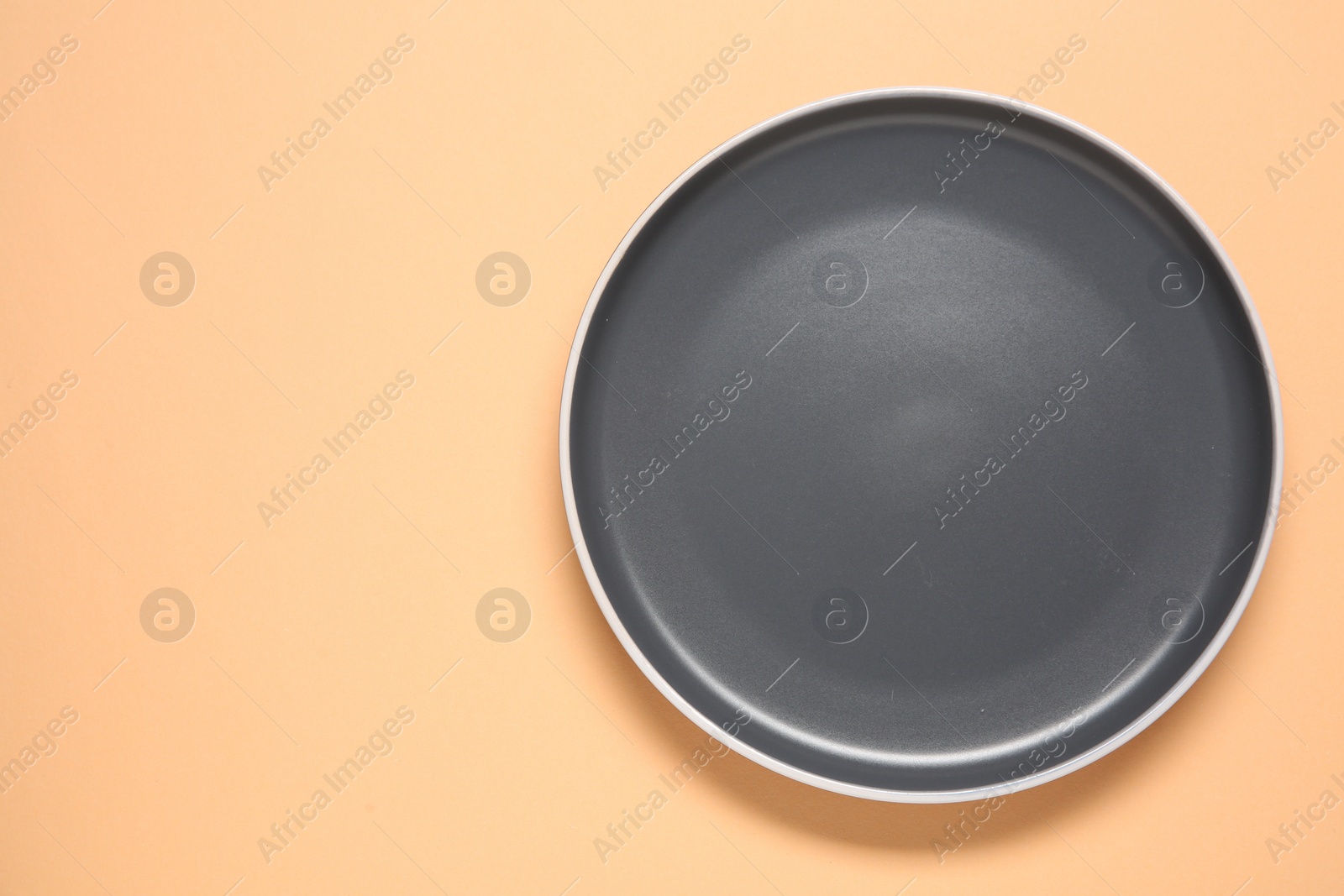 Photo of One grey ceramic plate on beige background, top view. Space for text