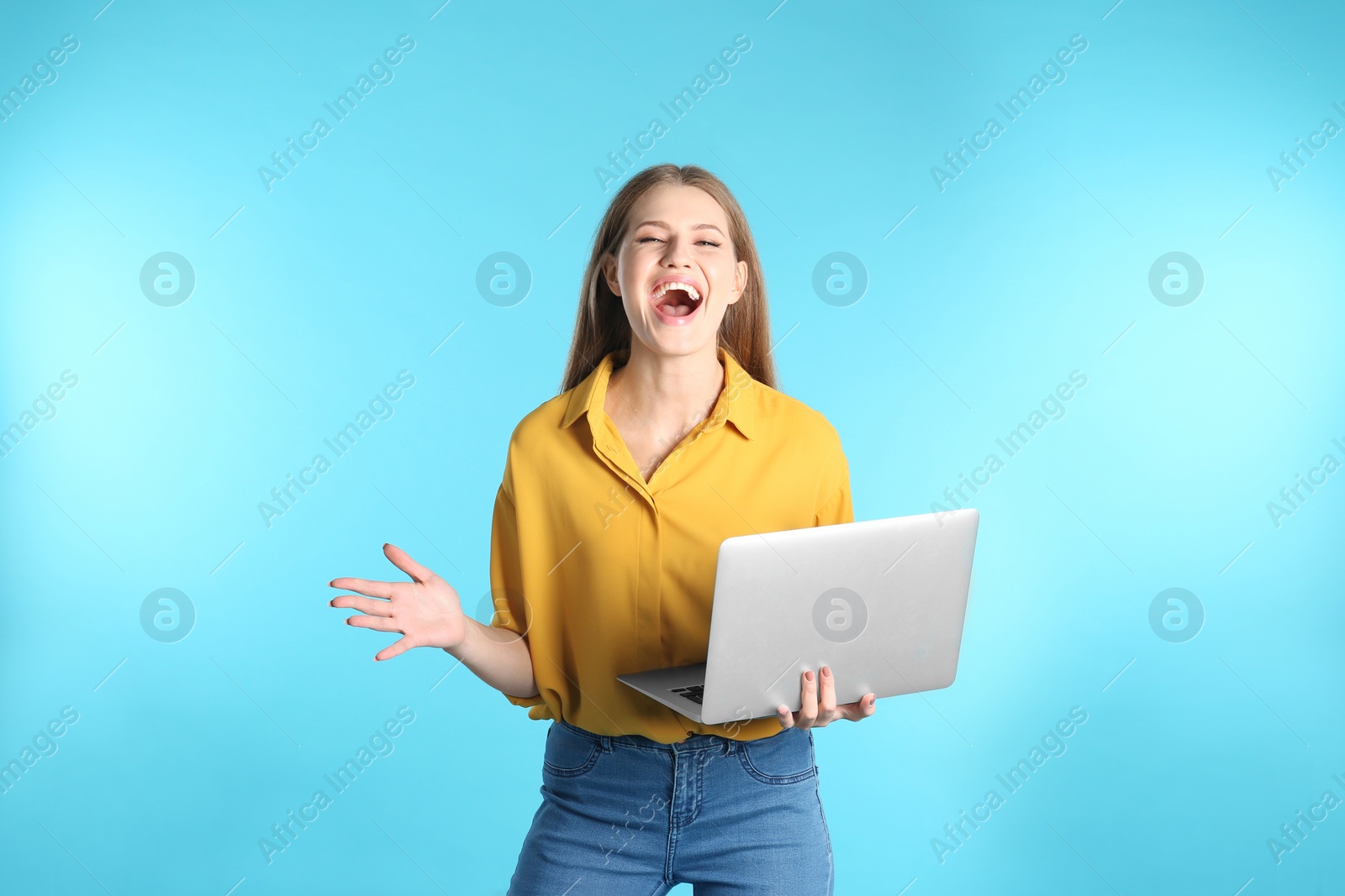 Photo of Emotional young woman with laptop celebrating victory on color background