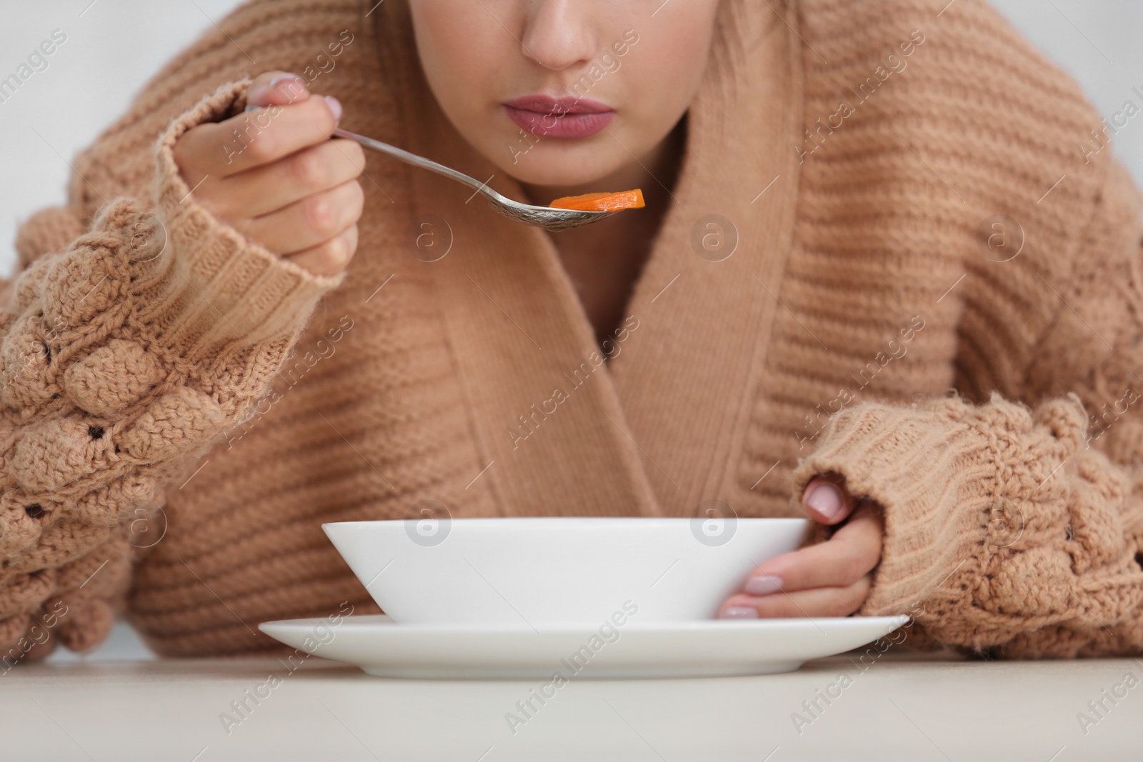 Photo of Sick young woman eating soup to cure flu, closeup