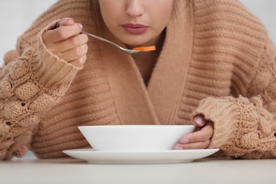 Sick young woman eating soup to cure flu, closeup