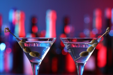 Photo of Martini glasses with cocktail and olives in bar, closeup