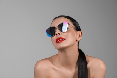 Photo of Attractive woman in fashionable sunglasses against grey background. Space for text