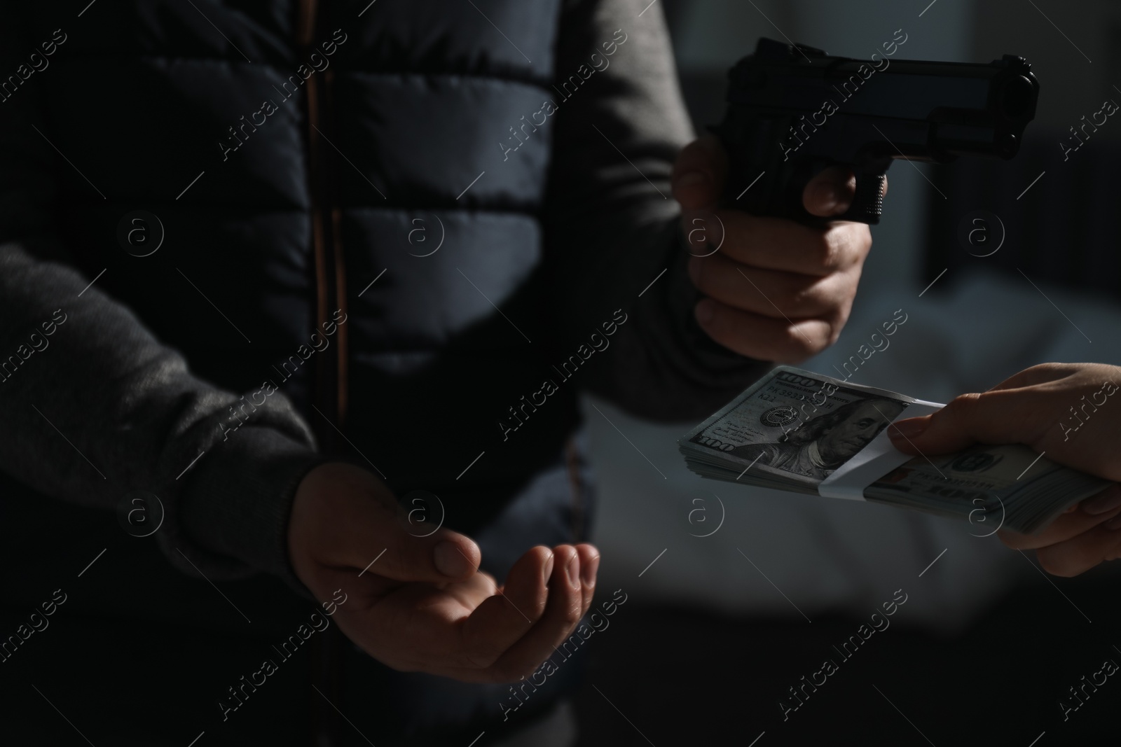 Photo of Woman giving money to criminal with gun indoors, closeup. Armed robbery