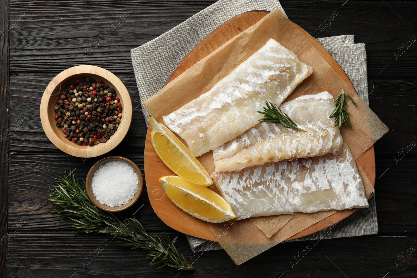 Photo of Fresh raw cod fillets, spices and lemon on wooden table, flat lay