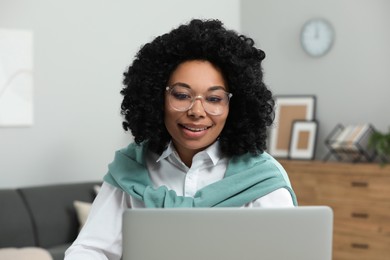 Photo of Happy young woman using laptop at home