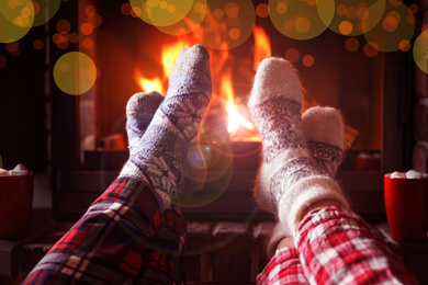 Image of Couple in pajamas resting near fireplace indoors, closeup. Winter vacation