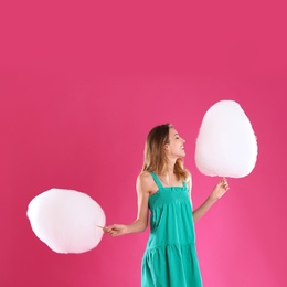 Photo of Happy young woman with cotton candies on pink background