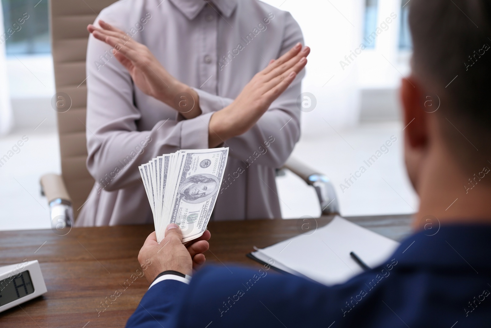 Photo of Woman refuses to take bribe money at wooden table, closeup