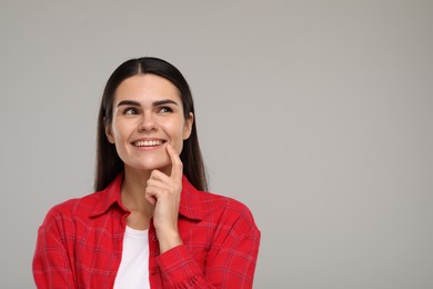 Young woman showing her clean teeth and smiling on light grey background, space for text