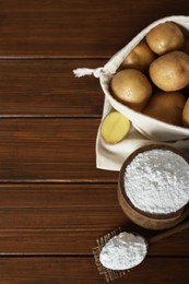 Photo of Starch and fresh raw potatoes on wooden table, above view