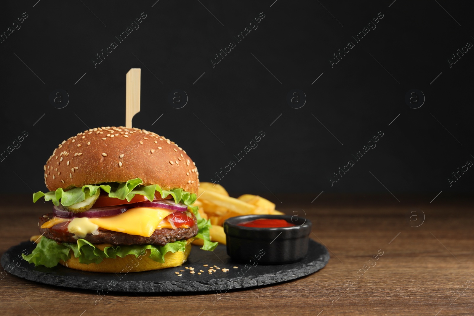 Photo of Delicious burger with beef patty, tomato sauce and french fries on wooden table, space for text