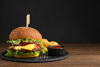 Delicious burger with beef patty, tomato sauce and french fries on wooden table, space for text