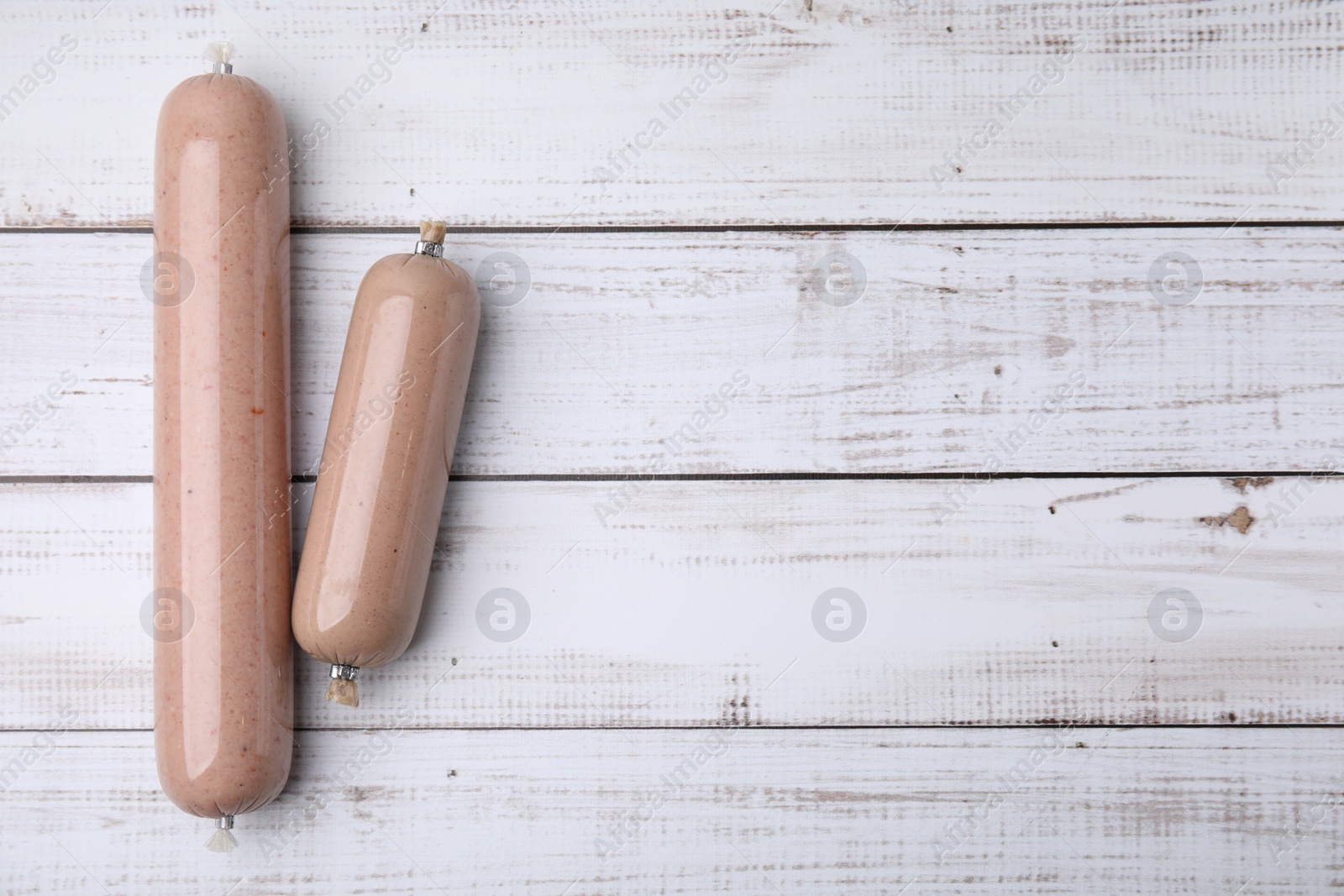 Photo of Delicious liver sausages on white wooden table, flat lay. Space for text