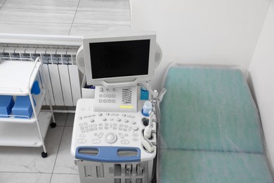 Photo of Ultrasound machine, medical trolley and examination table in hospital, above view