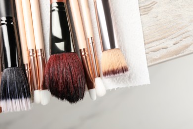 Photo of Set of different makeup brushes drying after cleaning on table, closeup